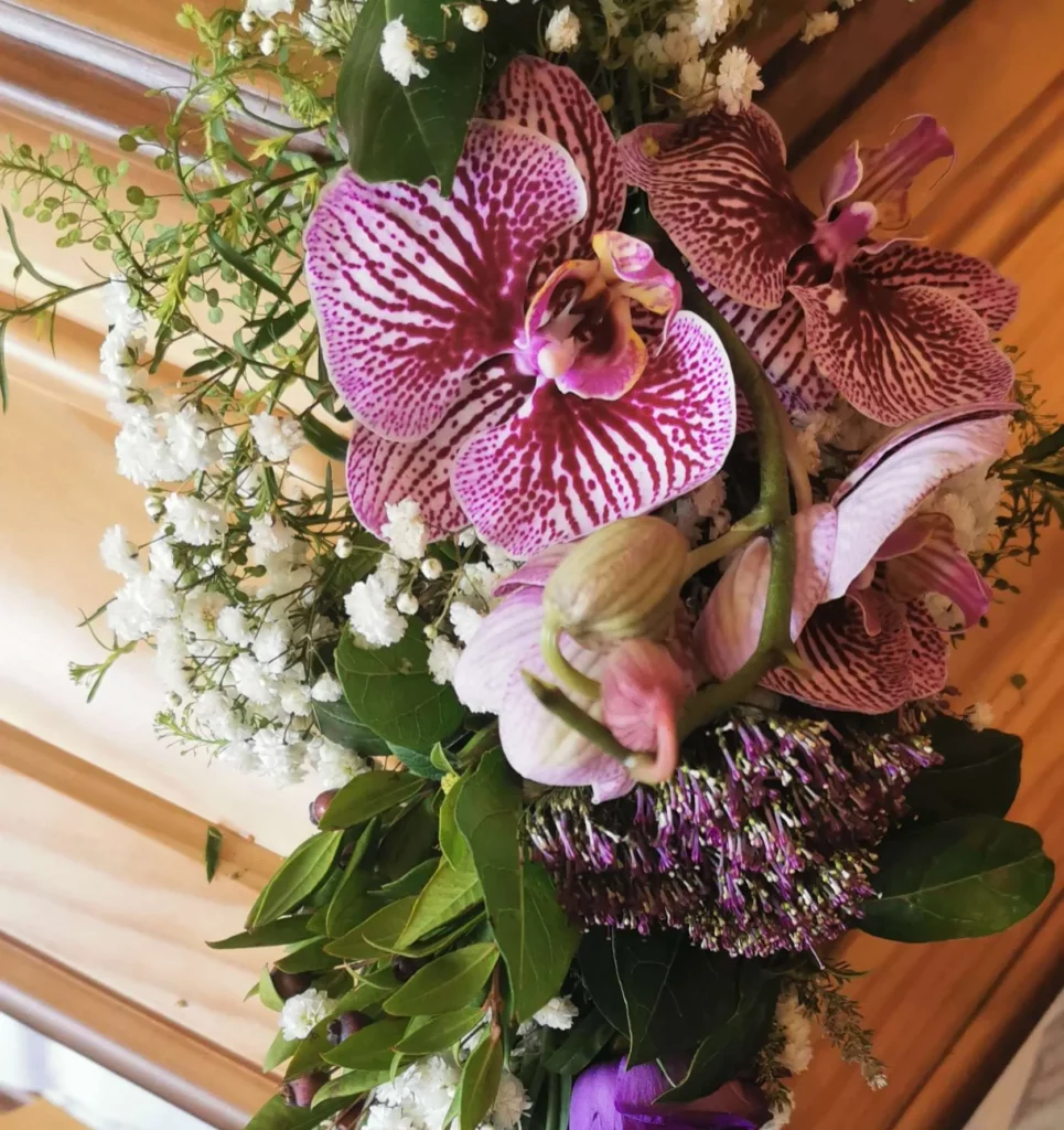 Composition florale de deuil avec orchidées sur un cercueil en bois