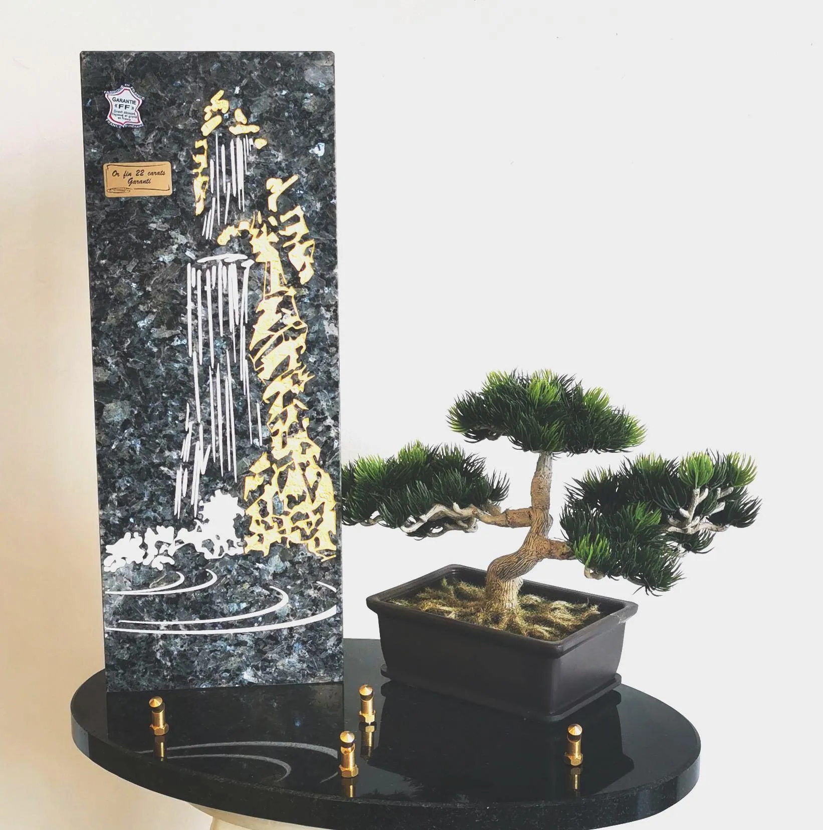 Plaque souvenir en granit gravée d'une cascade dorée à côté d'un bonsaï