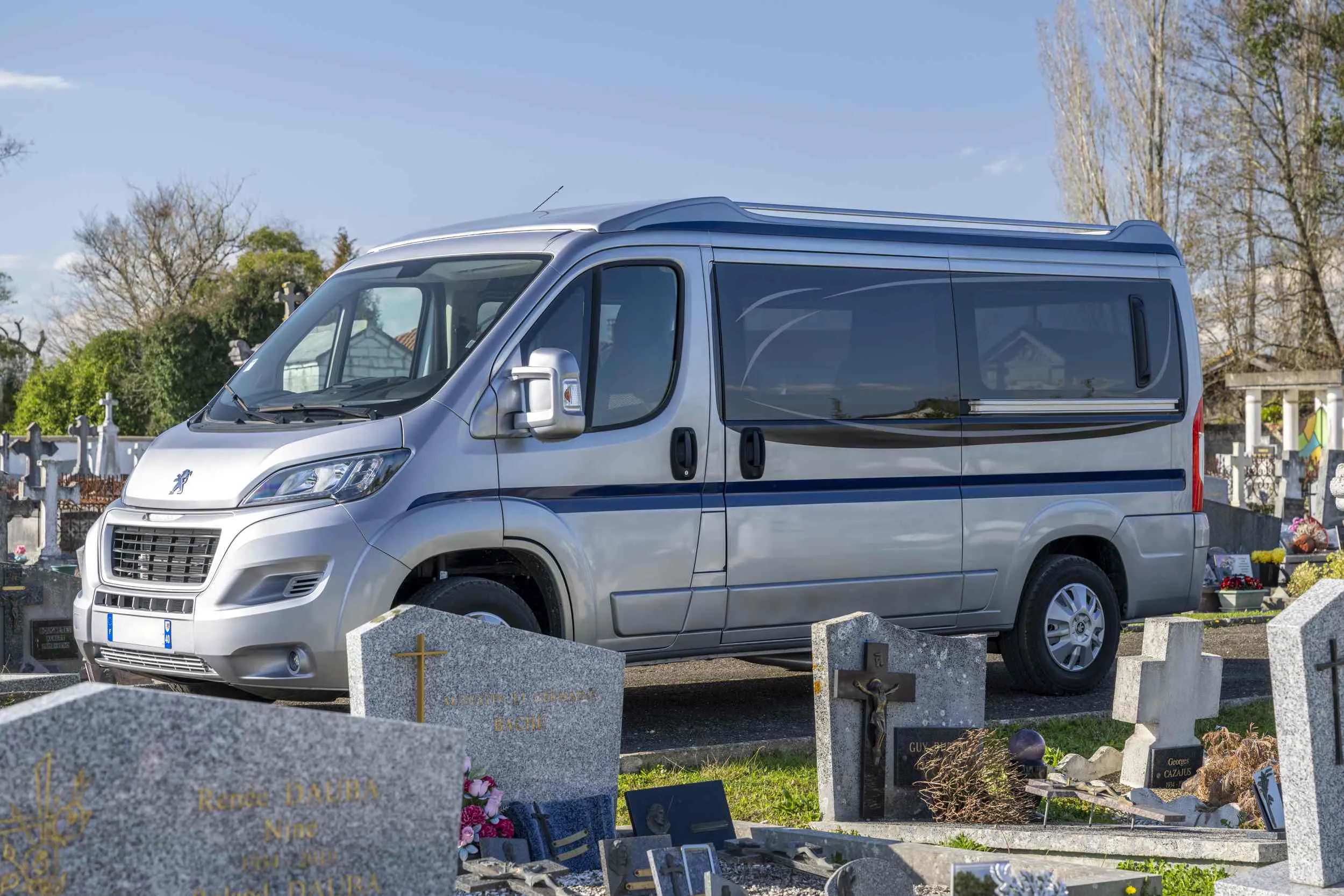 Corbillard gris stationné dans l'allée d'un cimetière