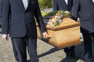 Porteurs funéraires en costume transportant un cercueil en bois orné de fleurs