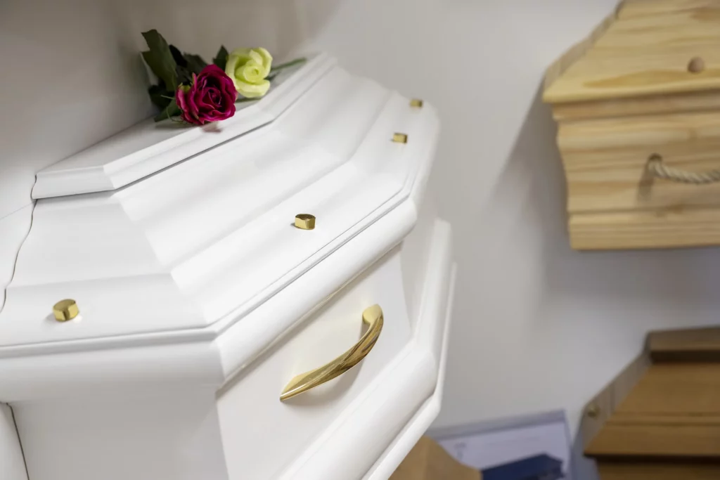 Cercueil blanc laqué orné de poignées dorées et d'une rose